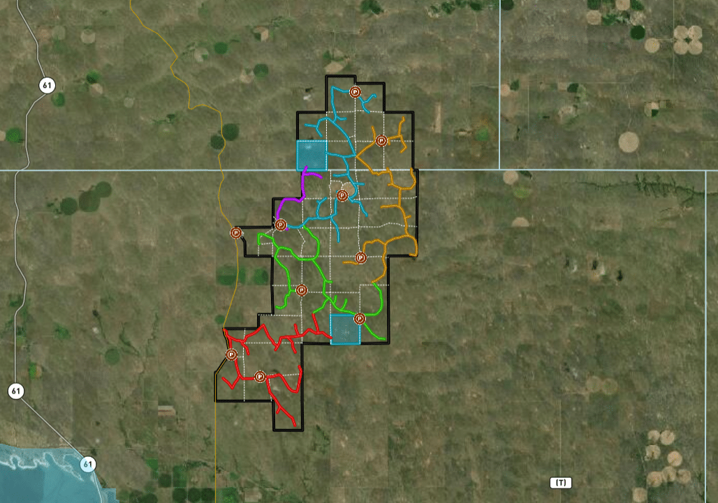A satellite map shows a rectangular area outlined in black with various colored, numbered sections inside—ideal as hunting property or cattle ranch. Surrounding land features fields, roads, and patches of vegetation.