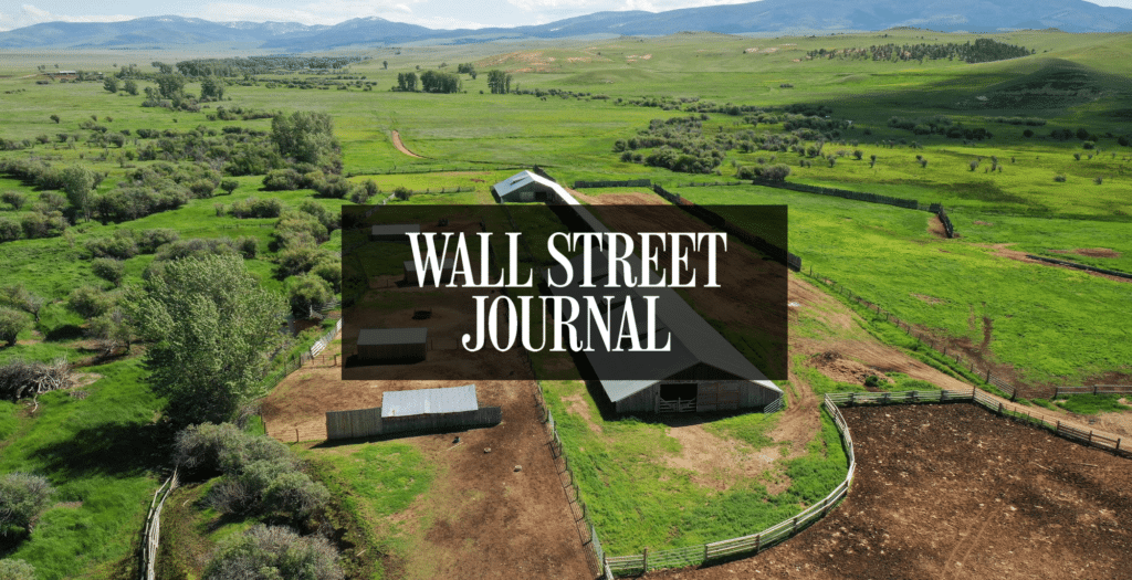 A rural cattle ranch with barns, fields, and distant mountains under a cloudy sky, overlaid with the text WALL STREET JOURNAL in bold white letters.