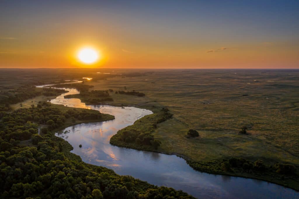 sunrise over Dismal River meandering through Nebraska Sandhills at Nebraska National Forest, aerial view of summer scenery
