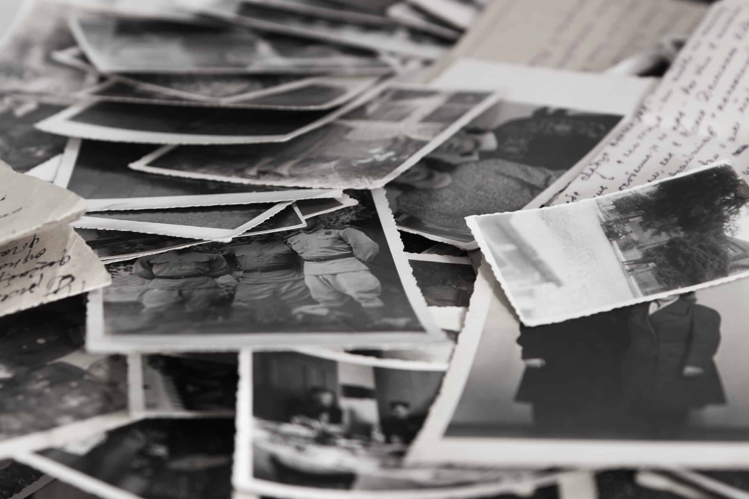 A pile of old black and white photographs and handwritten letters scattered on a surface, capturing scenes from a cattle ranch and recreational land, with people and landscapes partially visible and overlapping.