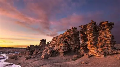 Rock formations rise from dry, sandy ground beneath a colorful sunset sky on this recreational land. Scattered rocks and a glowing horizon create the perfect backdrop for a potential cattle ranch or ranch for sale.