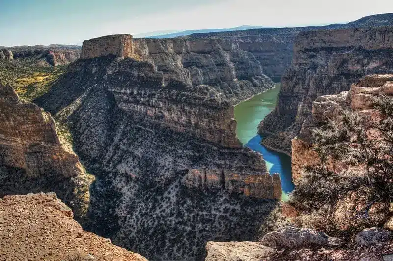 A deep river canyon with steep, rocky cliffs and sparse vegetation winds through rugged terrain under a clear sky, viewed from a high overlook—an ideal recreational land or hunting property.