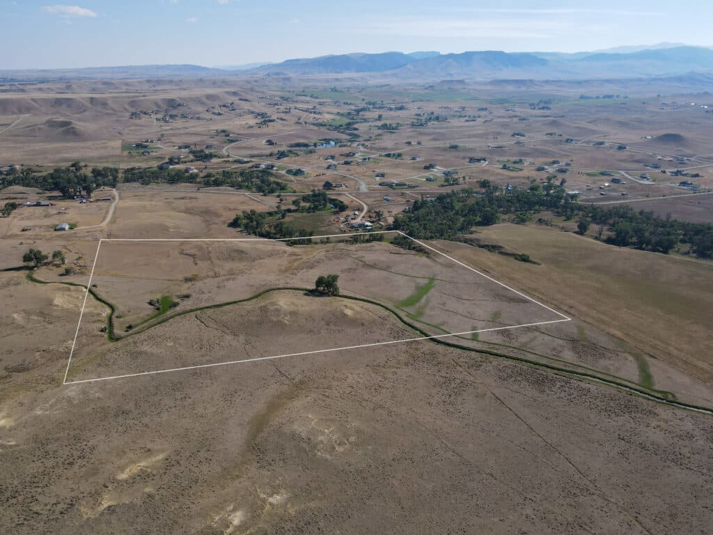 Aerial view of a dry, open landscape with hills and scattered houses; the large rectangular plot of land outlined in white marks the Rock Creek 40.